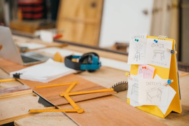 Üzerinde bir sandalye ve masa resmi olan sarı not defteri, üzerine iğnelenmiş. Mobilya tasarımı, çizim tarzı çizimler, marangoz yaratıcı konsept geliştirme için ideal