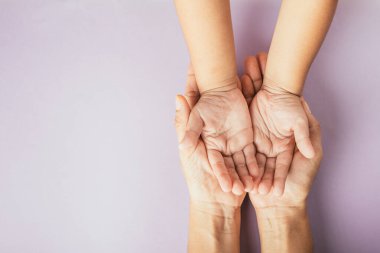 Ebeveyn ve çocuğun renkli bir arka planda el ele tutuşması. Aile Günü birlikteliğimizi kutluyor..