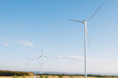 Dağ yel değirmeni çiftliğindeki türbinler doğa ile uyum içinde dönerler ve temiz enerji sergilerler. Modern rüzgar teknolojisi, sürdürülebilir gelişimi mavi gökyüzü altında yürütüyor.