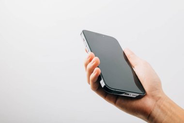 Siyah akıllı telefonun boş ekran görüntüsünü tutan bir adam, beyaz arka planda izole edilmiş siyah bir cep telefonunu tutan bir el, web sitesi tasarım uygulaması