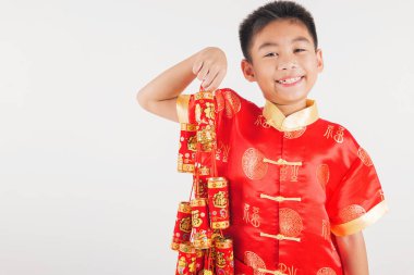 Kırmızı Cheongsam Qipao giymiş küçük bir çocuk neşeli bir gülümsemeyle dekoratif havai fişekler tutuyor. Parlak beyaz bir arka plan, Çin Yeni Yıl geleneklerini kutlamak için biçilmiş kaftan..