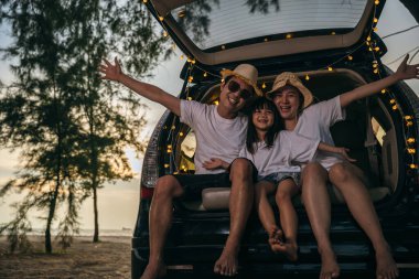 Asyalı bir aile gün batımında arabalarıyla sahilde oturuyor. Tatillerde ve tatillerde kendilerini tuhaf hissediyorlar. Baba, anne-kız iyi hafta sonları tatilleri. Plajda iyi eğlenceler. Yaz tatili kamp gezisi