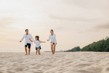 Aile babaları ve çocuklar sahilde gülüp oynuyorlar. Gülümseyen baba ve mutlu anne ile oğlu ve kızı kaygısız yaz tatillerinde neşeli ve mutlu anlar yaratıyorlar..