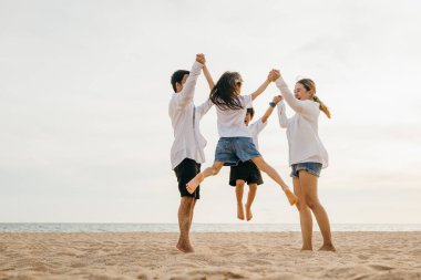 Asyalı bir ailenin, anne ve babalarının çocuklarını kucaklayıp çarpıcı okyanus zeminine atladığı sahilde heyecan doluyor. Aile neşesinin ve birlikteliğimizin mükemmel bir portresi..