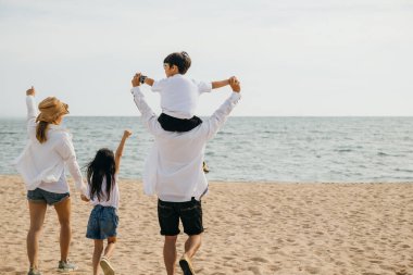 Gün batımında, deniz sahilinde dört kişilik mutlu bir aile, kollarını kaldırarak ayakta duruyor. Baba, kaygısız bir sahil tatilinin neşesini ve birlikteliğini simgeleyen oğlunu omuzlarında taşır. Aile sahilde tatilde.