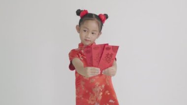 Çin Yeni Yılı. Mutlu Asyalı Çinli kız gülümsemesi kırmızı Cheongsam Qipao marka Angpao kırmızısı bir hediye paketi beyaz arka planda izole edilmiş geleneksel elbise içinde portre şeklinde bir çocuk.