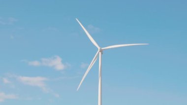 Çayırda bir dağdaki yel değirmeni çiftliği temiz enerjiye doğru küresel değişimi temsil eder. Verimli türbinler, sonsuz mavi gökyüzü altında sürdürülebilir kalkınmayı teşvik eden modern teknolojiye örnek teşkil ederler..