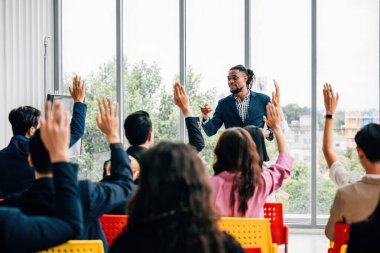 İş dünyasından profesyoneller sorularla meşgul olurken, toplantı odasında dinamik bir strateji oturumu başlıyor. Eller havaya, meslektaşların ve çalışanların aktif katılımını işaret ediyor.