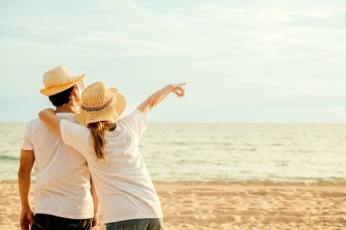 Sahilde yan yana duran Asyalı çift, sevgilisini kucaklayan mutlu genç kadın, deniz kenarında balayı tatili geçmişi, birbirine aşık çift, deniz kenarında dinleniyor.