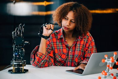 Bir sınıfta siyah bir genç öğrenci bir mühendislik projesi için robot kolu öğrenir ve kontrol eder. Zeka ve beceri göstererek teknolojideki yeniliği kucaklıyor. Robot el. Yenilik