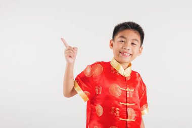 Kırmızı Cheongsam gibi giyinmiş gülümseyen Asyalı çocuk bir parmağını beyaz zeminde tutuyor. Çin Yeni Yıl teması için ideal, neşeyi, geleneği ve neşeli tezahüratı sembolize ediyor..