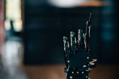 Geleceksel tasarımı gösteren siyah, gerçek bir robot el bir masaya temas eder. Modern robotlarda yapay zeka evrimini ve teknolojik yeniliği sembolize eder..