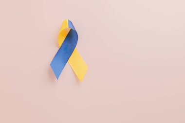 Küresel destekle Dünya Down Sendromu Günü ve Otizm Bilinci. Pembe arka planda sarı ve mavi bir farkındalık kurdelesi Down Sendromunu sembolize eder..