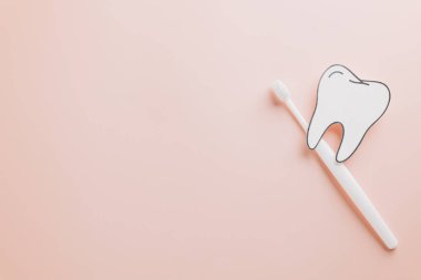 Diş kâğıdı kesimi ve diş fırçası pastel pembe diş hekimi günü için. Dünya Diş Hekimliği Günü için diş bakımı, ağız sağlığı ve diş hijyenine dikkat çekiliyor..