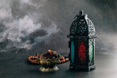 Kutsal Ramazan süslemeleri, dua boncukları ve fenerlerle dolu. Karanlık arka planda huzurlu bir Ramazan ayini için güzel düzenlenmiş..
