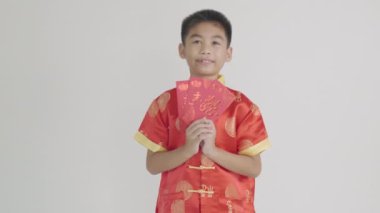 Kırmızı Cheongsam Qipao 'lu gülümseyen Asyalı çocuk elinde kırmızı bir zarf tutarak Çin Yeni Yılı' nda iyi şansı simgeliyor. Gelenek ve neşeyi yansıtan canlı bir portre. Beyaz arkaplanda izole.