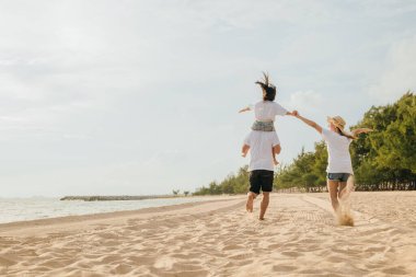 Tatilde mutlu bir aile. Baba, anne ve çocuklar omuz omuza gezip, yaz kumsalında koşuyorlar, aileler çocukları boynunda taşıyorlar, aileler günbatımında yazın tadını çıkarıyorlar.
