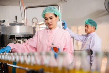 Fabrikada QC mühendisleri cam şişe meyve suyu üretimini inceliyor. Denetlemeleri, üretim sürecinde birinci sınıf kaliteyi ve hijyeni garanti ediyor..