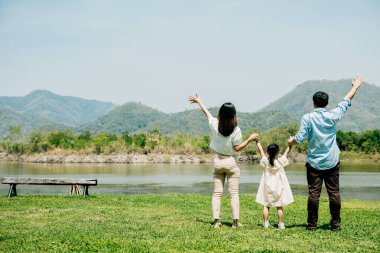 Asyalı aile babası anne ve kızı göl kıyısında dururlar. Parkta güneşli bir gün, yaşam tarzı ebeveynleri ve çocukları yaz yolculuklarında doğanın tadını çıkarırlar. Aile rahatlığı.