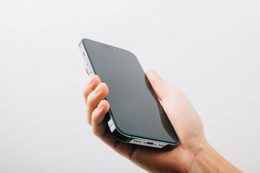 Beyaz arka planda izole edilmiş siyah bir cep telefonu tutan bir el, siyah akıllı telefon tutan bir adam boş ekran görüntüsü, web sitesi tasarım uygulaması