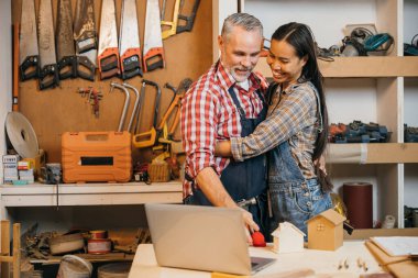 Birkaç marangoz, aletler ve marangozluk projeleriyle çevrili rahat ahşap dükkanlarında sevgi dolu kucaklaşmalarını paylaşıyor. Küçük işletme sahipleri olarak, birlikte çalışmaktan zevk alın, mobilya ve el işi parçaları oluşturun.