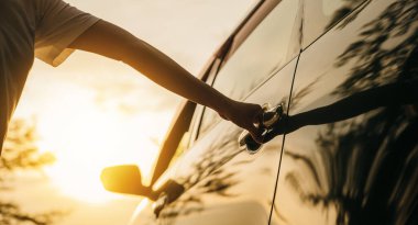 Gün batımında bir arabanın kapısını açan genç kadın elini kapat. Sürücü koltuğuna geçmek için el ele tutuşun. Seyahat konsepti