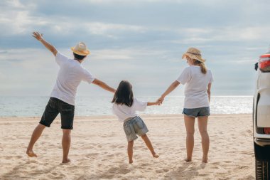 Mutlu aile üç, kumlu sahilde el ele dururlar, anne ve babalar el ele tutuşurlar çocuklarını geri götürürler, tatillerde araba kullanırlar, yaz gezileri, aile günlerinde birlikte eğlenirler.