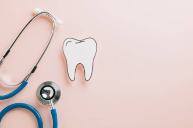 Dişçi günü için pastel pembe üzerine steteskoplu kağıt kesiği diş. Dünya Sağlık Kampanyaları için yaratıcı model tasarımlar yoluyla diş sağlığı, ortodonti ve oral bakımı vurgulamak.