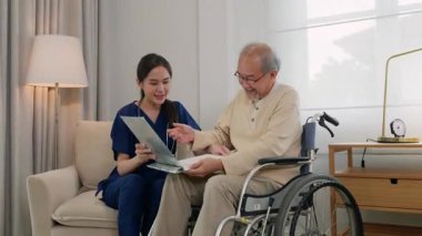 Hasta dosyasını taşıyan Asyalı kadın doktor tekerlekli sandalyede oturan yaşlı adama, sağlık hizmetlerine ve tıbbi tedaviye ilişkin sonuçları anlatırken hasta dosyasını tutuyor.