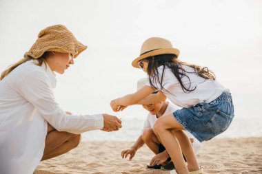 Mutlu anne ve çocuklar sahilde eğleniyor. Aile tatilleri neşe kahkahaları ve tasasız anları betimler. Gerçek insanların duyguları bu gün batımı portresinde yer alıyor.