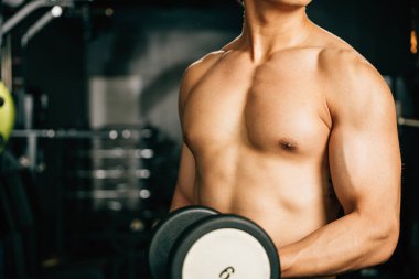Spor salonundaki ekipmanlarla çalışan bir adam, enerjisi ve motivasyonu onu sınırlarını zorlamaya ve sağlıklı ve güçlü bir vücut elde etmeye itiyor. Fitness GYM Sağlıklı spor yaşam tarzı konsepti