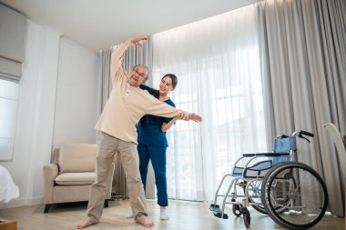Old senior man enjoys training with physiotherapist for outstretched arms at home, Asian physical therapist patient nursing helping elderly exercising arm stretch, Rehabilitation of disabled concept