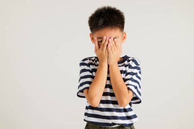 Asyalı bir portre. Depresyondaki kötü ruh hali içinde. Yüzü ellerle kaplanmış ve tek gözü parmaklarıyla dışarı bakıyor.