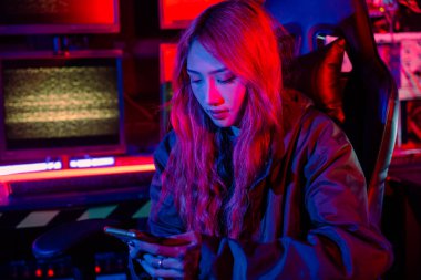 Kadın hacker. Kapüşonlu Asyalı bir kadın bilgisayar başında çalışıyor ve cep telefonu daktilo yazma programlama sisteminde çalışıyor. Hacker 'ın internette gezinmesi şifreyi kırmak için akıllı telefonlu kötü amaçlı yazılım kullanır, Oyun siberi