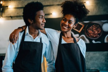 Kafe sahibi siyah bir barista ve sahibi dizüstü bilgisayardan tedarik emri planlıyorlar. İşletme başarısı finansal planlama amacıyla kahve dükkanında çalışma takvimi takım çalışması tartışılıyor.