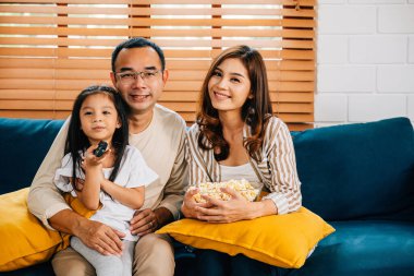 Oturma odasında patlamış mısırlı bir film izleyen aile için aile zamanı eğlenceli ve rahatlatıcıdır. Baba, anne, oğul, kız, hepsi mutlu bir şekilde gülümsüyor..