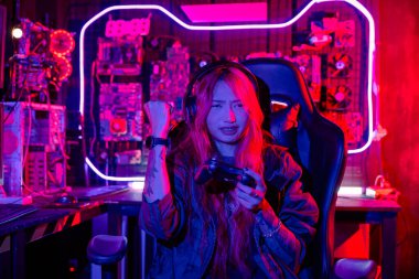 Sanal turnuva için joystick kumandası kullanan oyuncu çevrimiçi video oyunu oynuyor, bilgisayar neon ışıklı karanlık oda, kadın evde canlı yayında esport oyunu konsolu oynarken oyun kulaklığı takıyor
