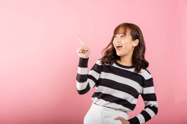 Asyalı mutlu bir portre ayakta duran güzel bir genç kadın jest yapıyor. İki parmak yukarıda bir şey sunuyor. Stüdyo çekimleri pembe arka planda, fotokopi alanı ile izole edilmiş.