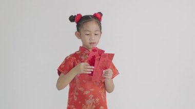 Çin Yeni Yılı. Mutlu Asyalı Çinli kız gülümsemesi kırmızı Cheongsam Qipao marka Angpao kırmızısı bir hediye paketi beyaz arka planda izole edilmiş geleneksel elbise içinde portre şeklinde bir çocuk.
