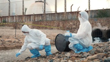 Nehirden gelen suyu test tüpü, koruyucu giysi içindeki bilim adamı veya biyolog ile örnekleyen ve maskesini koruyan ekolojist, analiz için endüstriden atık su örneği topluyor, sorun ortamı