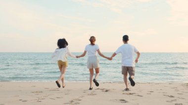 Mutlu arkadaşlar el ele tutuşup hayatın tadını çıkarıyorlar kumsalda birlikte özgürlüğün tadını çıkarıyorlar gün batımında tatil tatilinde genç Asyalı kadın ve erkek yaz seyahatinde, insanların yaşam tarzı