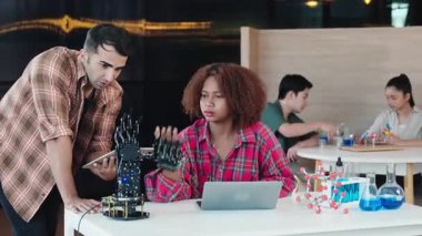 Sınıfta öğretmenlik yapan bir öğrenci robot kolu yapan bir öğrenciye yardım eder. Tasarım ve teknoloji derslerinde keşif yeniliği ve kodlama becerilerini teşvik etmek. Robot el. Yenilik ve teknoloji kavramı