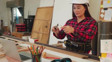 Kırmızı ekose gömlekli bir kadın ahşap atölyesinde bıçakla kalem kesiyor. Marangozluk, DIY projeleri ve işçilik üzerine odaklı afişler için ideal, Carpenter