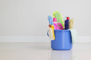 Rutin temizlik gereksinimleri. Deterjan şişeleri, fırçalar ve diğer temizlik malzemeleriyle dolu mavi plastik kova oturma odasında, ev işleri ve günlük ev işleri için hazırlanıyor.
