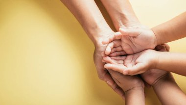 Birlikteliği ve güveni kucaklayan Stüdyo, izole edilmiş bir arkaplanda aile ellerinin üst görüntüsünü yakalıyor. Ebeveynler ve çocuklar Aile ve Veliler Günü 'nü simgeleyen boş bir yer tutuyorlar..