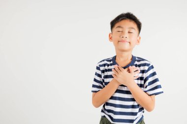 Kalp meditasyonuna yakın el ele tutuşan ve beyaz arka planda kısa süre izole edilmiş stüdyoda gülümseyen mutlu genç çocuk, birincil çocuk inanç ve sevgi minnettarlığına inanır.