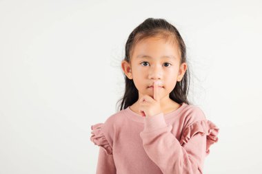 Genç kız dudaklarını parmaklıyor sessiz jest yapıyor, Mutlu Asyalı anaokulu çocuğu sessiz kalmak için sessizliği işaretliyor, sessiz stüdyo çekimi beyaz arka planda izole edilmiş, fotokopi alanı ile.