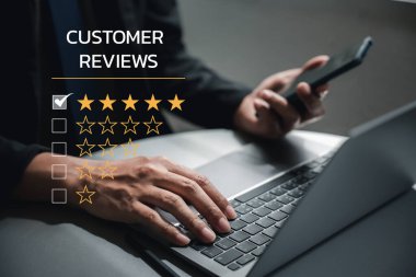İş mükemmelliği kaliteli hizmet ile elde edilir. Geri bildirim değerlendirmesi ve müşteri memnuniyeti anketi için 5 yıldızlı akıllı telefon ve laptop kullanan bir adam eli