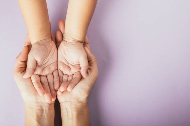 Aile günü konsepti, aile ve çocuğun renkli bir arka planda el ele tutuşması. Beraberliğimizi kutluyoruz..