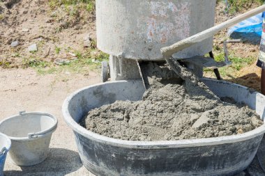 Somut hazırlıklar devam ediyor: çimento karıştırıcı gri havan ve kumu pürüzsüz bir karışım haline getiriyor.